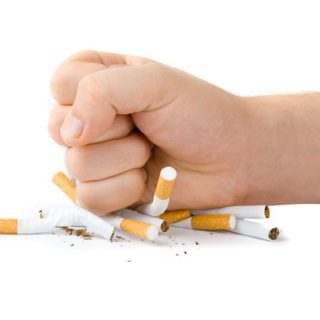 Male fist with many cigarettes isolated on white
